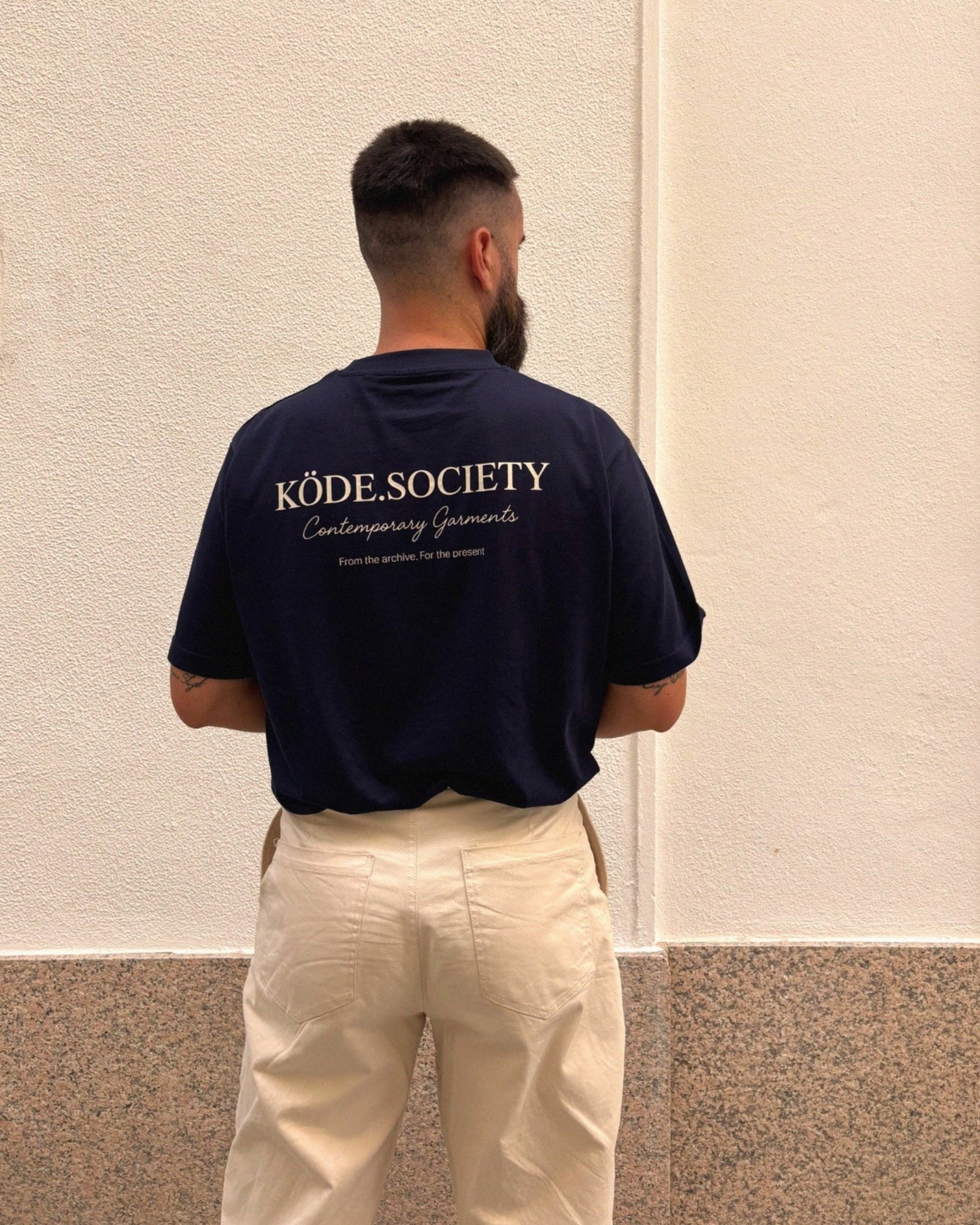 Prenda de algodón con diseño tipográfico elegante, capturada en una escena urbana limpia y cálida.