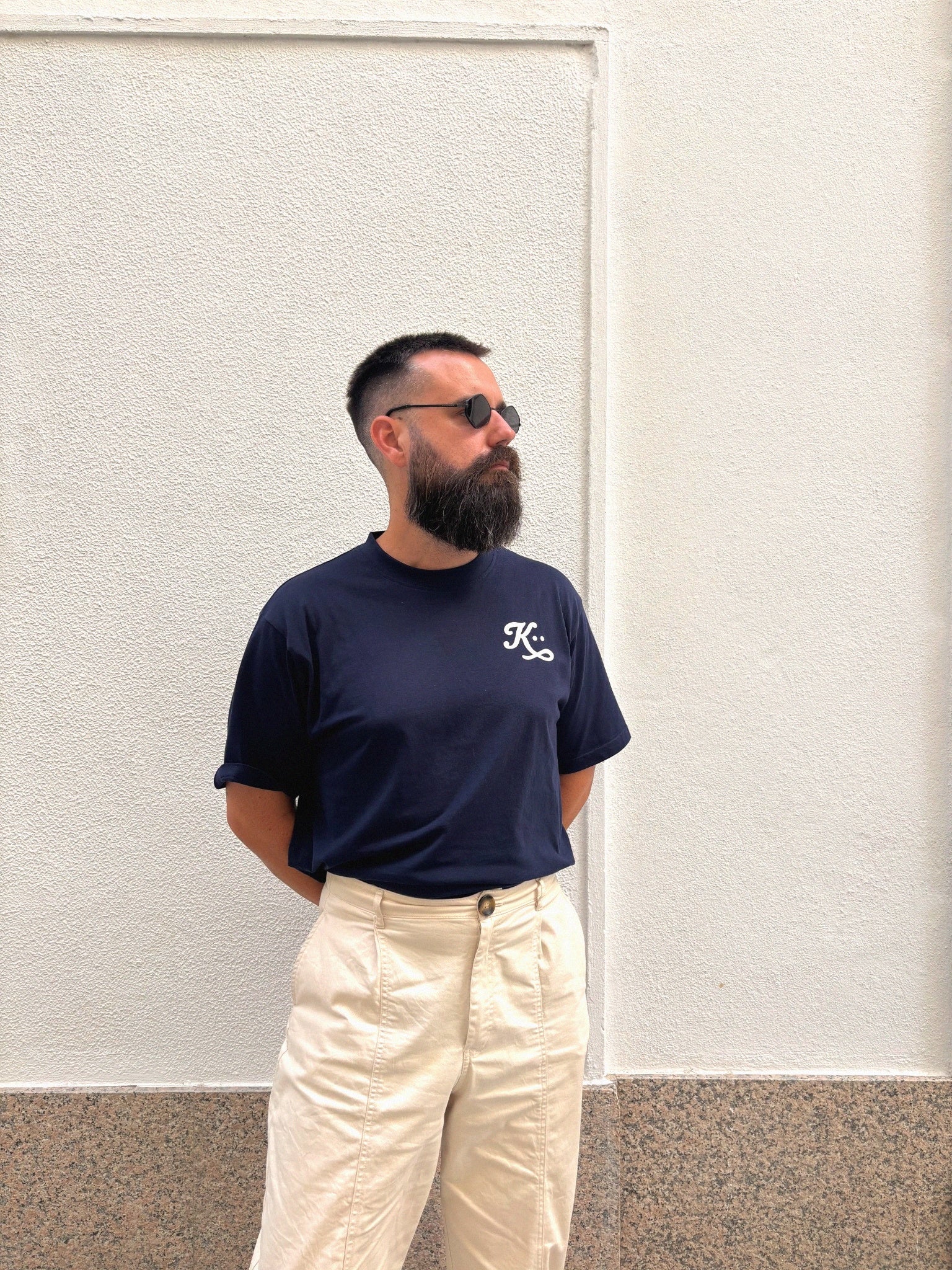 Contraste entre la sobriedad del outfit y el fondo neutro, reforzando el mensaje de elegancia atemporal.