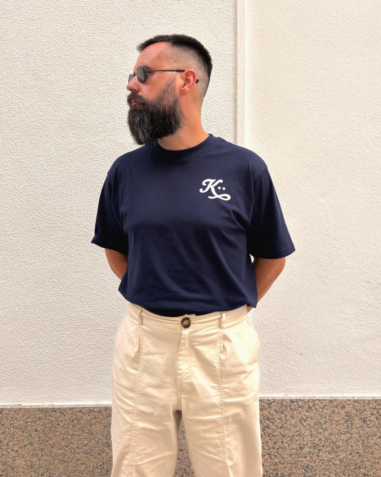 Imagen editorial capturada en luz natural frente a una pared blanca. Look relajado con silueta limpia.