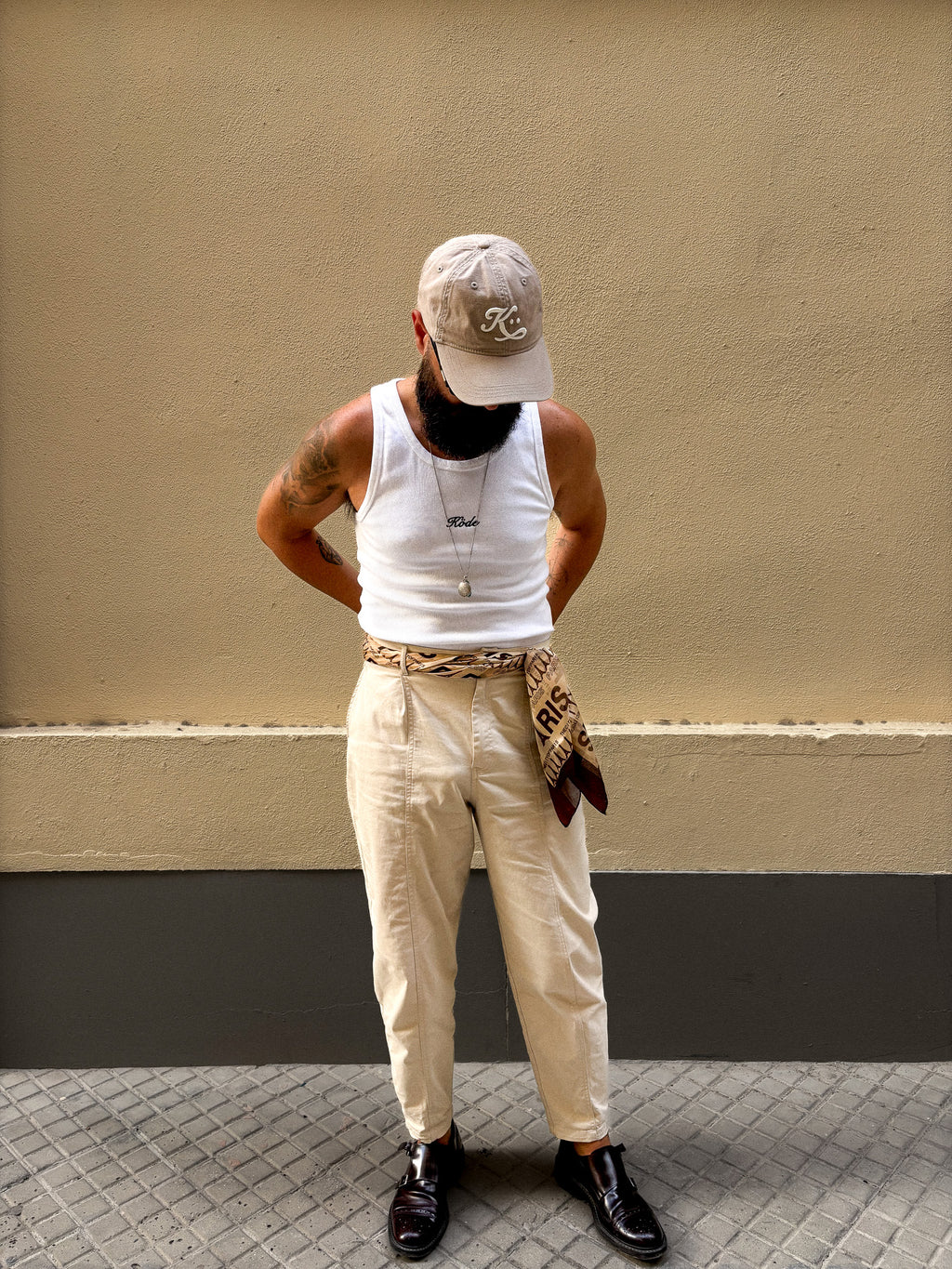 Look editorial en movimiento con tank top blanca KÖDE, pantalón claro y pañuelo, estética retro premium.